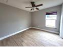 Bright bedroom featuring wood-look flooring, a modern ceiling fan, and a window that allows natural light to fill the space at 2309 30Th W Ave, Bradenton, FL 34205