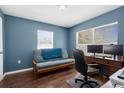 Cozy bedroom with blue walls, wood floors, a futon, and a desk with dual monitors for a workspace at 2396 Malibu Ln, North Port, FL 34286