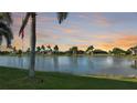 Breathtaking water view at sunset, showcasing the tranquil lake and palm tree-lined landscape of the community at 24342 Saragossa Ln, Punta Gorda, FL 33955