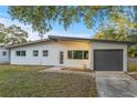 A charming, one-story home with a white exterior, gray trim and a well-manicured front lawn at 3169 Bellevue St, Sarasota, FL 34237