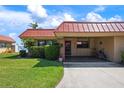 Charming condo exterior featuring lush lawn, landscaping, a covered parking area, and proximity to the water at 3859 Catalina Dr, Bradenton, FL 34210