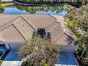 Aerial view of a well-maintained house with a large clay roof, situated near a tranquil lake at 4136 Cascade Falls Dr, Sarasota, FL 34243