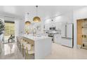 Bright, all-white kitchen features an island with seating and stainless steel appliances at 4146 Westbourne Cir, Sarasota, FL 34238