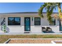Close up of charming home with white stucco and black trim with chairs in front of blue door at 11 1St E St, Nokomis, FL 34275