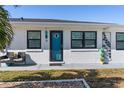 Close up of charming home with white stucco and black trim with chairs in front of blue door at 11 1St E St, Nokomis, FL 34275