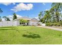 Inviting single-story home with a lush green lawn, palm trees, a two-car garage, and a vinyl privacy fence at 13339 Flaherty Ave, Port Charlotte, FL 33981