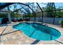 Screened-in pool area with a private pool, waterfall feature, brick pavers and outdoor furniture at 13339 Flaherty Ave, Port Charlotte, FL 33981