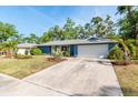 Inviting home with an attached two-car garage and a lengthy concrete driveway, surrounded by lush greenery at 2933 Mayflower St, Sarasota, FL 34231