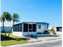 Inviting mobile home with a screened-in porch, complemented by palm trees and well-maintained landscaping at 3414 Spanish Oak Ter, Sarasota, FL 34237