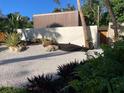 Modern landscaping features a crushed gravel driveway, lush greenery, and privacy walls at 4408 Midnight Pass Rd, Sarasota, FL 34242