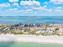 Aerial view showcasing beachfront condos along a pristine shoreline with crystal-clear water and sunny skies at 5055 Gulf Of Mexico Dr # 115, Longboat Key, FL 34228