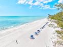 Picturesque beach view with clear turquoise water, white sand, and colorful beach umbrellas at 5055 Gulf Of Mexico Dr # 115, Longboat Key, FL 34228
