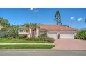 Beautiful pink single-story home featuring a three-car garage and a well-manicured front lawn at 5270 Far Oak Cir, Sarasota, FL 34238