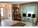 Cozy living room featuring tile flooring, a large window with curtains, bar stools, and ample space at 5714 Garden Lakes Dr, Bradenton, FL 34203