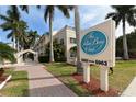 The Palm Bay Club condo community featuring lush landscaping, a paver walkway, and exterior signage at 5963 Midnight Pass Rd # 355, Sarasota, FL 34242