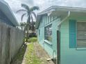 Side yard view showing the house's turquoise exterior, a window, and a glimpse of the backyard at 109 Colonia W Ln, Nokomis, FL 34275