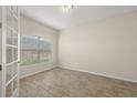 Bright, empty bedroom with tile flooring and a large window allowing natural light at 11499 Renaissance Blvd, Venice, FL 34293