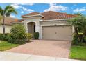 Attractive home showcasing a well-manicured lawn and a paver driveway, complemented by a tan exterior at 11499 Renaissance Blvd, Venice, FL 34293