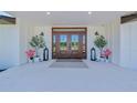 Inviting entryway featuring double doors, sconces, potted plants, and an entrance mat at 1208 Oak Hammock Rd, Sarasota, FL 34240