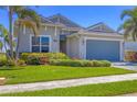 Charming single-story home with lush green lawn and colorful landscaping leading up to a two-car garage at 17675 Azul Dr, Lakewood Ranch, FL 34202