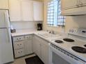 Classic kitchen features white appliances and cabinets, complemented by a black and white checkered window covering at 2340 Canal Dr # G-35, Bradenton, FL 34207