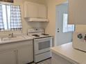 Classic kitchen features white appliances and cabinets, complemented by a black and white checkered window covering at 2340 Canal Dr # G-35, Bradenton, FL 34207