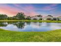 Picturesque view of the tranquil pond reflecting a colorful sunset over the property at 2628 Sapphire Blue Ln, Bradenton, FL 34211