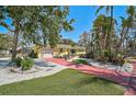 Exterior view of a yellow single-story home with lush tropical landscaping, driveway and manicured lawn at 322 S Washington Dr, Sarasota, FL 34236