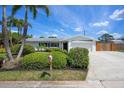 Inviting single-story home featuring a well-kept lawn, tropical palm trees, and a spacious driveway leading to the garage at 5523 Scotia Pl, Sarasota, FL 34231