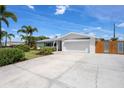 Beautifully landscaped front yard with lush greenery, tall palm trees, and a spacious driveway leading to a two-car garage at 5523 Scotia Pl, Sarasota, FL 34231