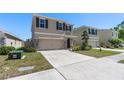 Home exterior featuring a long driveway, two-car garage, beige paint, stone accents, manicured lawn and landscaping at 5868 Calla Lilly Dr, Sarasota, FL 34232