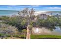 Aerial view showcases a waterfront property with a wooden walkway, lush greenery, and scenic ocean views at 8555 Heron Lagoon Cir, Sarasota, FL 34242