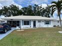 Charming home featuring a white exterior, white tile roof, blue shutters, and a well-maintained lawn at 1007 Pussywillow Ln, Bradenton, FL 34208