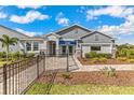 Beautiful single-story home showcasing stone details, a fenced front yard, and vibrant landscaping at 10717 Tippecanoe Pl, Parrish, FL 34219