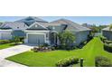 Beautiful single-story home with a gray exterior, lush landscaping, and a two-car garage at 11021 Blue Magnolia Ln, Parrish, FL 34219