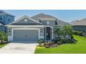 Inviting single-story home featuring a gray color scheme and attractive landscaping at 11021 Blue Magnolia Ln, Parrish, FL 34219