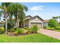 Charming single-story home with well-manicured lawn, lush landscaping, and a brick-paved driveway at 11214 Sandhill Preserve Dr, Sarasota, FL 34238