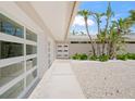 Exterior view showing the home's entrance, with white doors, palm trees, and a gravel landscape at 1186 Center Pl, Sarasota, FL 34236