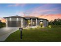 One story home at dusk featuring a well-manicured lawn and modern architectural details at 13552 Boatbill Ln, Port Charlotte, FL 33981