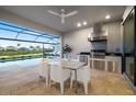 The outdoor kitchen includes a built-in grill, stainless steel appliances, and scenic views of pool, patio, and lake at 16626 Paynes Mill Dr, Lakewood Ranch, FL 34211