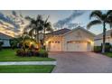 Inviting home with a brick driveway, two-car garage, and well-maintained landscaping with palm trees at 21287 Sandal Foot Dr, Venice, FL 34293