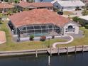 Aerial view of a waterfront home with a screened-in pool, dock, and beautifully landscaped backyard at 2817 La Mancha Ct, Punta Gorda, FL 33950