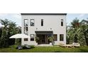 A peaceful backyard with modern outdoor furniture that is surrounded by tropical plants and lush grass at 3847 30Th S Ave, St Petersburg, FL 33711