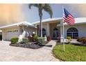 View of a well-maintained home exterior with an American flag and an attached two-car garage at 832 Carnoustie Dr, Venice, FL 34293