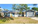 Charming single-story home with blue exterior, stone accents, well-manicured lawn, and an attached white one car garage at 8731 Peggy Ave, Sarasota, FL 34231