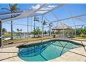 Outdoor pool area featuring a screen enclosure, tiki hut, and picturesque water views at 10616 Ayear Rd, Port Charlotte, FL 33981