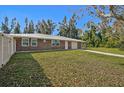 A single-story brick home displaying the well-maintained lawn and manicured landscape, capturing the home's charm at 12305 Harland St, North Port, FL 34287
