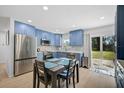 Modern kitchen features stainless steel appliances, blue cabinets, and a dining area with a sliding glass door at 12305 Harland St, North Port, FL 34287