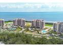 Panoramic aerial view of luxury beachfront condos with pools, tennis courts, golf course, and ocean views at 3030 Grand Bay Blvd # 323, Longboat Key, FL 34228