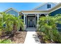 A welcoming front porch with decorative columns, palm trees, and a charming wreath on the front door at 4308 Fly Rod Ter, Parrish, FL 34219